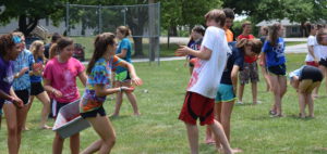Teens playing a lively outdoor game on a sunny day.