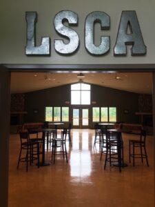 Interior of a hall with LSCA letters above the entrance and tables inside.