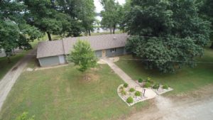 A single-story house surrounded by trees and a well-kept yard.