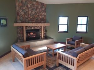 Cozy living room with stone fireplace and wooden furniture.
