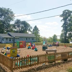 A vibrant playground with various play equipment surrounded by a wooden fence.