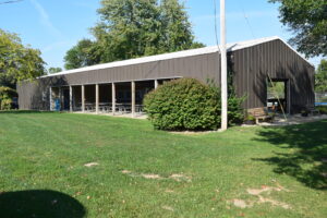 A wooden building with large windows and green lawn.