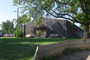 Rustic wooden barn surrounded by green trees and grass.