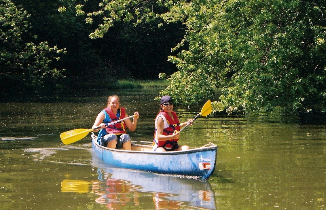 Two people enjoying canoeing on a calm lake surrounded by greenery.